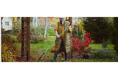 žena hrabající listí na zahradě na podzim