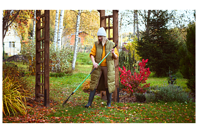žena hrabající listí na zahradě na podzim