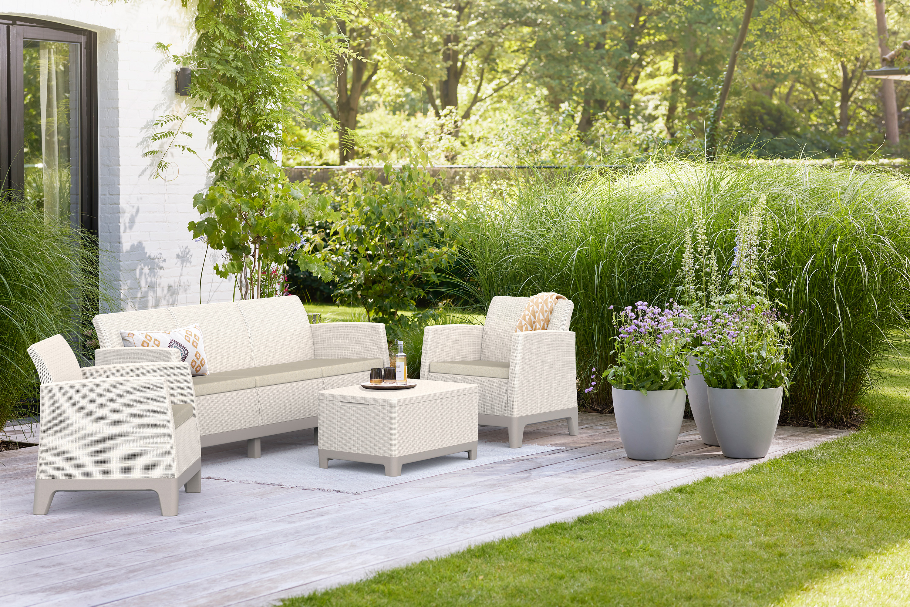 Zahradní nábytek Scandi Forma Pebble Grey-Soft Beige tvořený pohovkou, dvěma křesly a stolkem na terase v zahradě