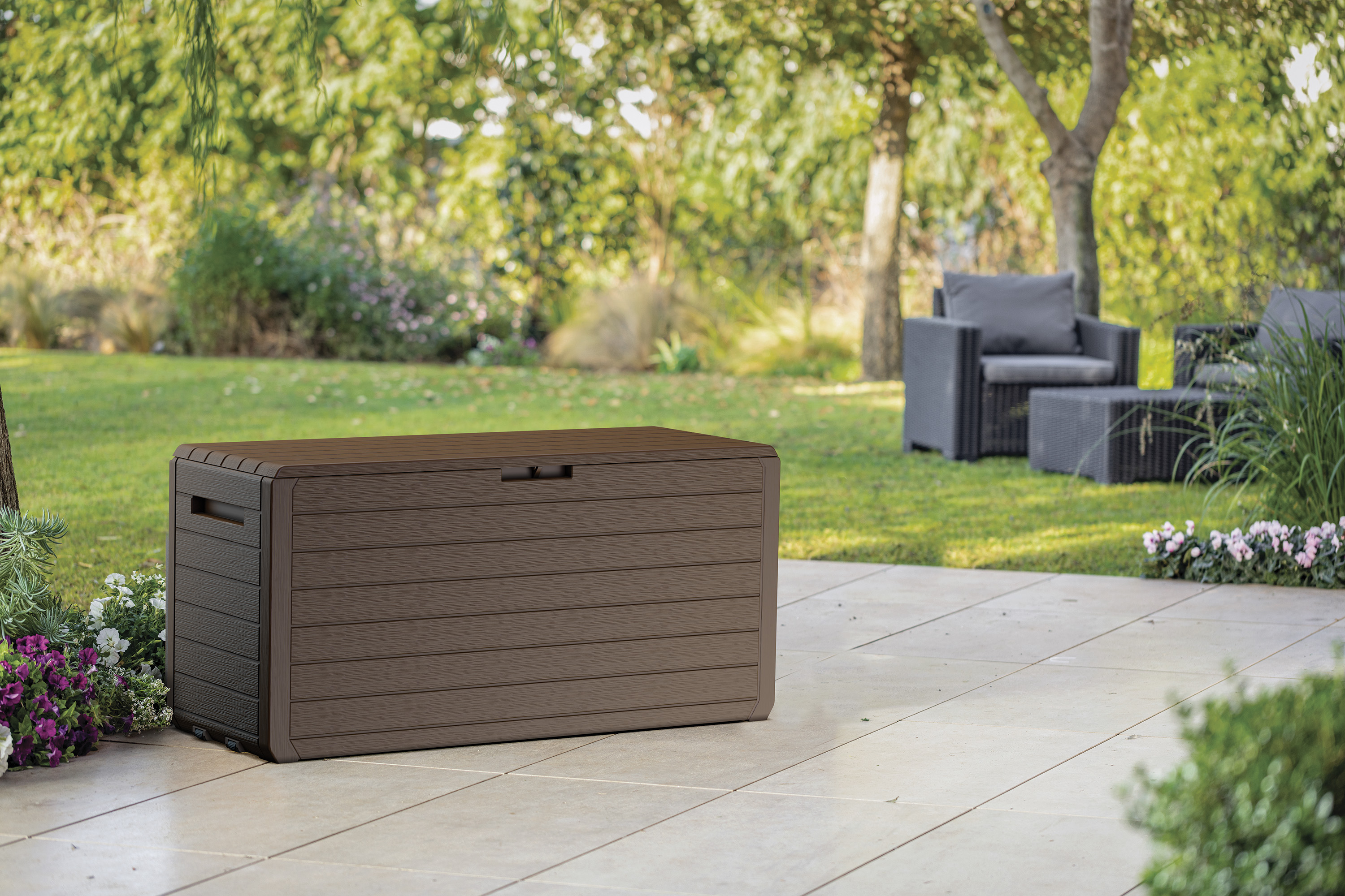 Hnědý zahradní úložný box ATLAS 270L Keter umístěný na terase v zahradě