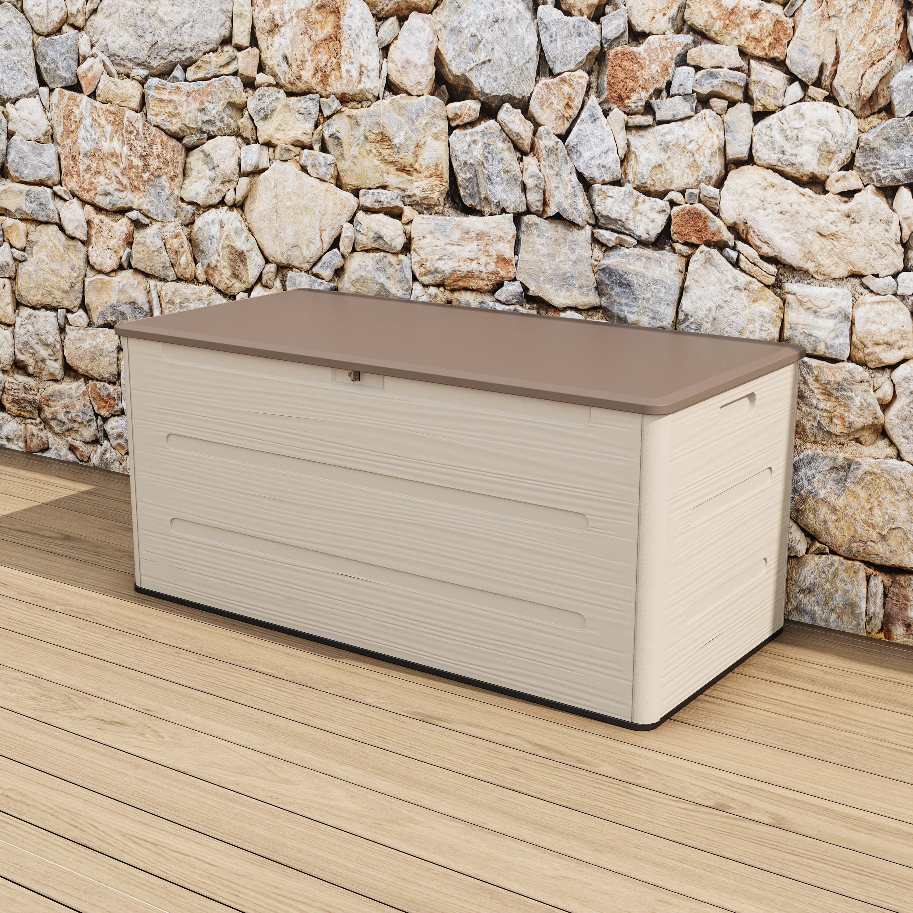 Zahradní úložný box SIERRA 645 L Brown v hnědo-béžovém provedení stojící na dřevěné terase u kamenné zdi
