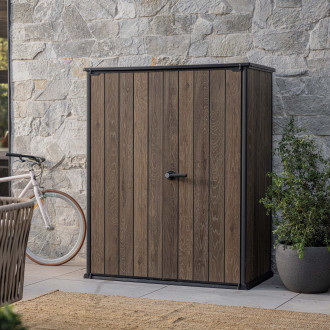 Zahradní skříň Deco Vertical 1400L Walnut v barvě dřeva s černým rámem umístěná na terase u kamenné zdi