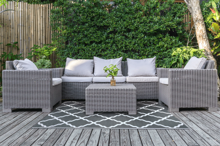 Šedý zahradní koberec 180x270cm Middle Gray - MOODME s geometrickým vzorem umístěný pod ratanovou sedací soupravou na terase