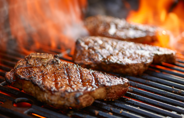 grillowanie stek&oacute;w na płonącym grillu 