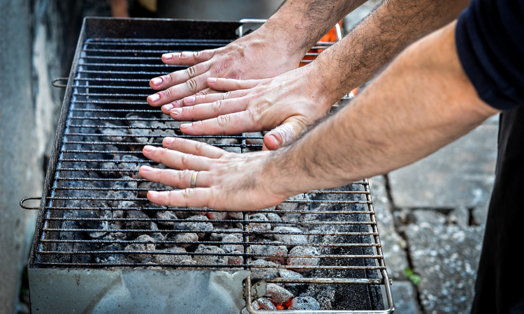 muži kontroluj&iacute;c&iacute; teplotu grilu rukama