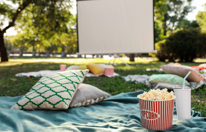 venkovn&iacute; kino zař&iacute;zen&eacute; na zahradě s barevn&yacute;mi pol&scaron;t&aacute;ři a dekami