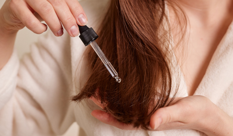 Kobieta aplikuje serum na końc&oacute;wkach włos&oacute;w