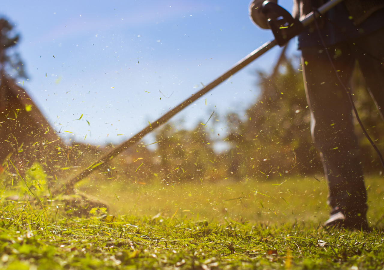 Muž seká trávu na plném slunci