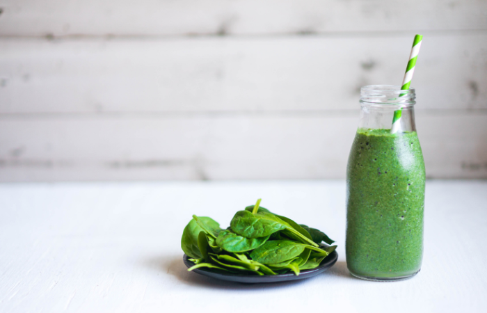 listy &scaron;pen&aacute;tu na tal&iacute;ři a vedle l&aacute;hev se &scaron;pen&aacute;tov&yacute;m smoothie