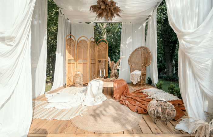 Zahradn&iacute; alt&aacute;n s rustik&aacute;ln&iacute; b&eacute;žovou dekorac&iacute; na piknik v zahradě, venkovn&iacute; design. Ratanov&yacute; n&aacute;bytek venku v pergole boho, modern&iacute; dom&aacute;c&iacute; dvůr. Letn&iacute; alt&aacute;n s př&iacute;rodn&iacute; rostlinou, dřevěn&yacute;m vybaven&iacute;m a dekami.