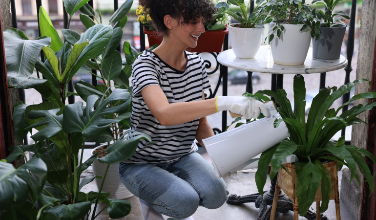 Kobieta podlewa swoje rośliny na balkonie
