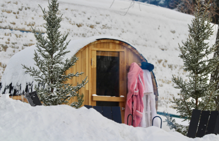 Pokryt&aacute; sněhem sudov&aacute; sauna s župany